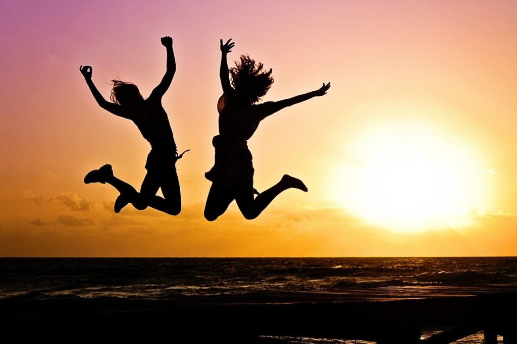 two people jumping into the air at sunset
