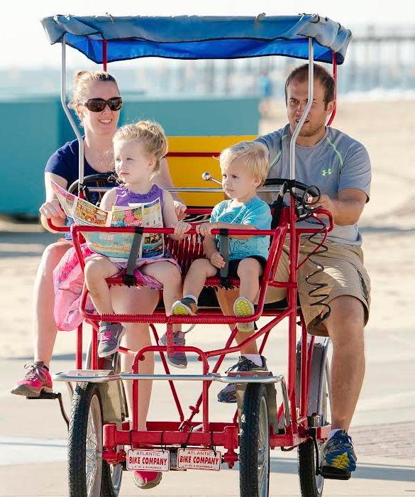 a family riding on a red cart down the beach